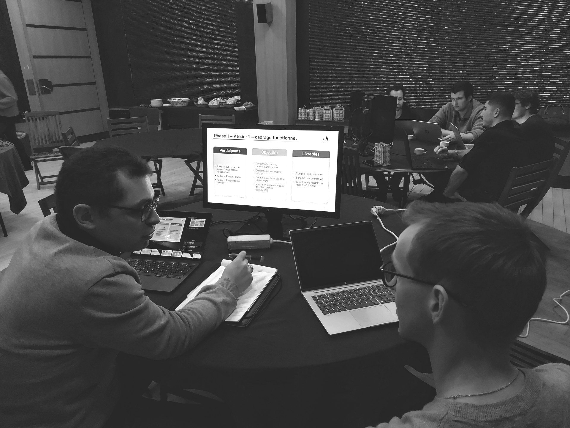 Two Ariovis consultants in a functional scoping workshop, in front of a slide listing participants, objectives and deliverables.